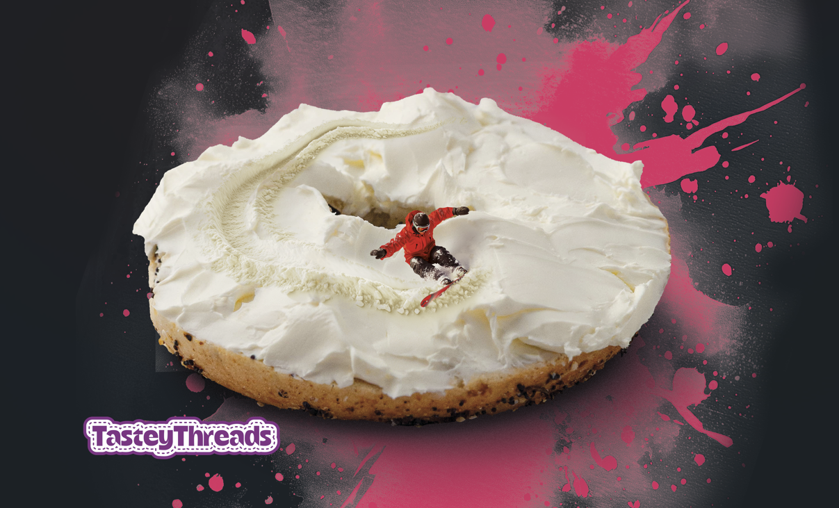 Tastey Threads Backcountry Bagel design, cream cheese on an everything bagel doubling as snow for the snowboarder to shred on